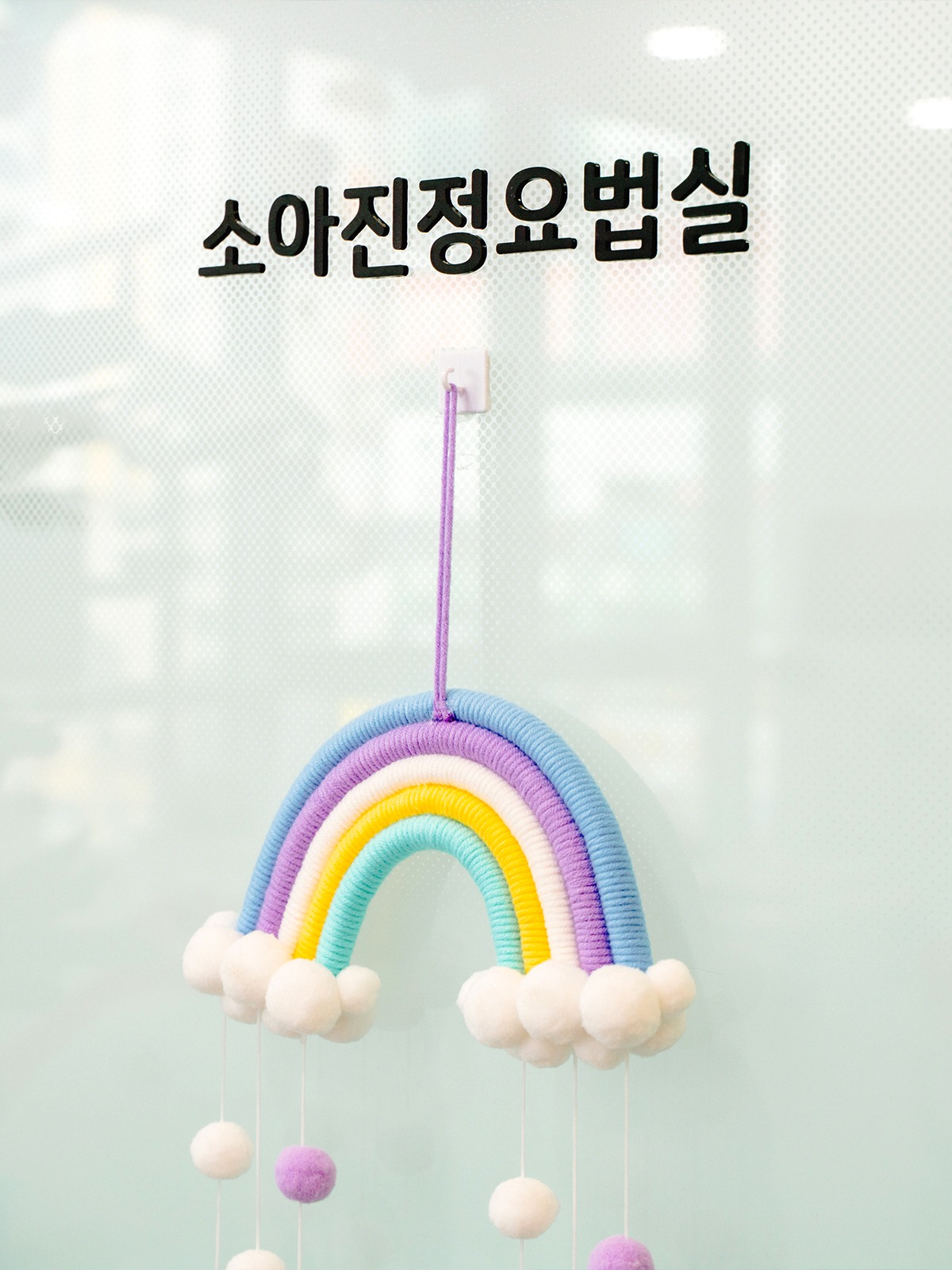 소아진정요법실 글자가 붙은 유리문에 무지개 모빌이 걸려 있다